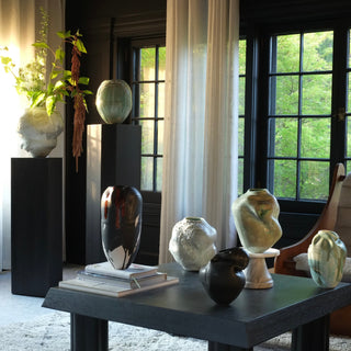 Decorative vases on a table with large windows in the background