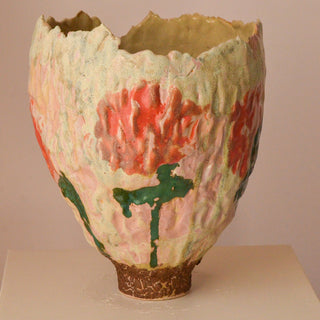 Ceramic vase with textured surface and colorful design on a plain background
